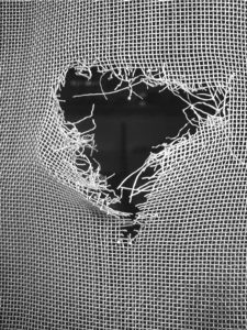 A broken screen door shown close up